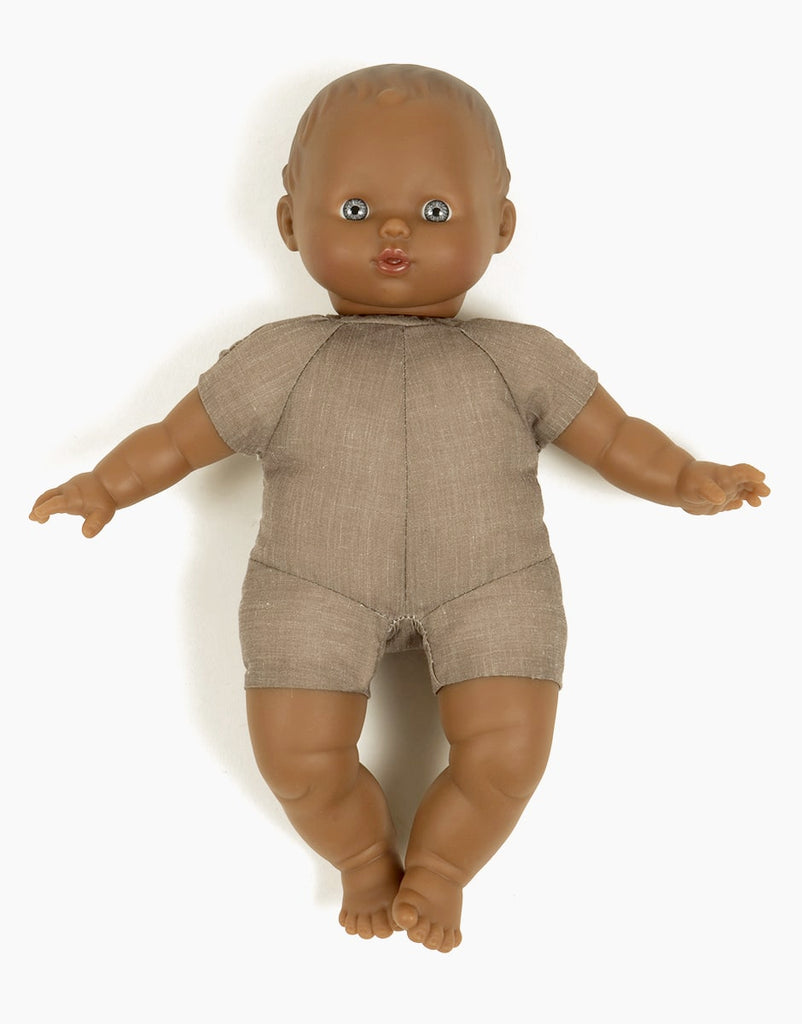 The Minikane Soft Body Doll (11") - Suzie is made from phthalate-free vinyl, features painted facial details, wears a taupe short-sleeved one-piece, and lies on a white background—ideal for imaginative play.