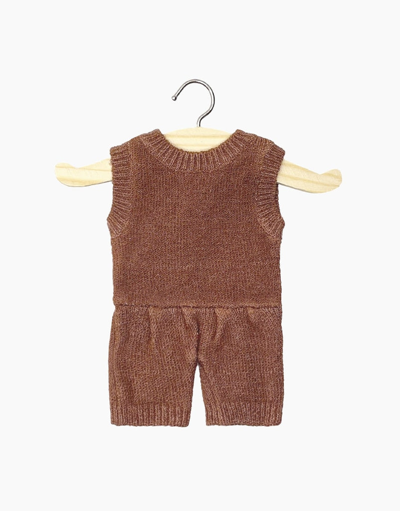 A Minikane | Orlando Heather Caramel Knit Romper Doll Clothing is hanging on a wooden hanger. The outfit includes a sleeveless top and matching shorts, crafted with exquisite knit composition. The background is white, highlighting the simplicity and coziness of this hand washable clothing set.