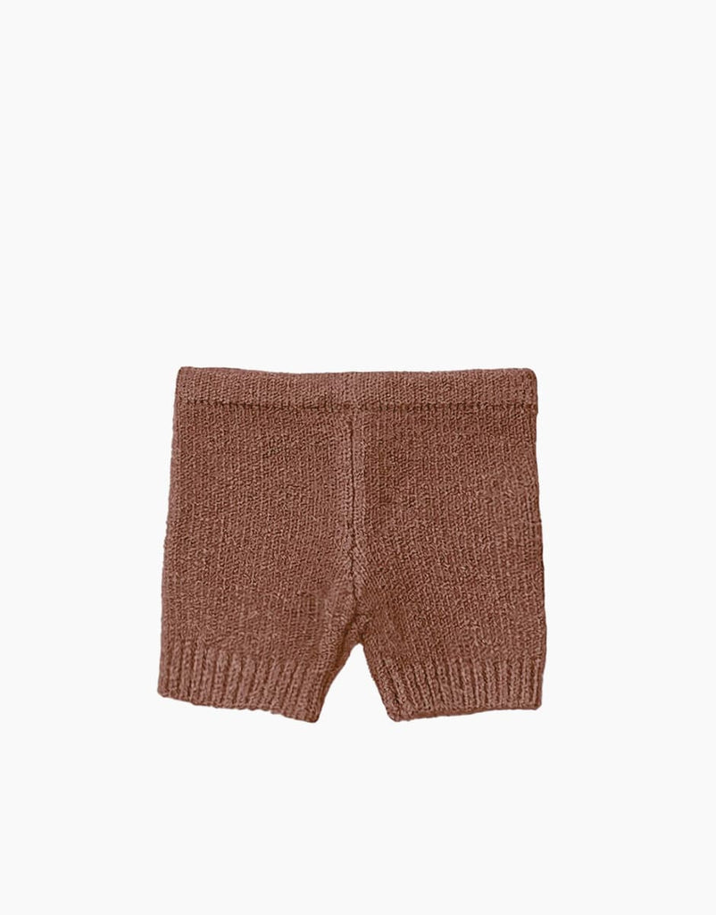 A pair of brown knitted shorts, featuring a subtle wool composition, laid flat against a white background. These Minikane Doll Clothing | Vito Shorts in Marl Caramel Knit have a simple design with an elastic waistband and a gentle knitted texture.