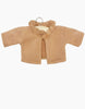 A small, tan-colored Minikane Doll Clothing | Claudia Cardigan in Brown Sugar Fleece Doll Clothing is displayed on a hanger against a white background. The cotton sweater features long sleeves and a ruffled neckline.
