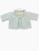 A light gray doll-sized jacket with long sleeves and a ruffled collar, showcasing exquisite French tailoring. The Minikane Doll Clothing | Claudia Cardigan in Green Tea Fleece is displayed on a wooden hanger against a plain white background.