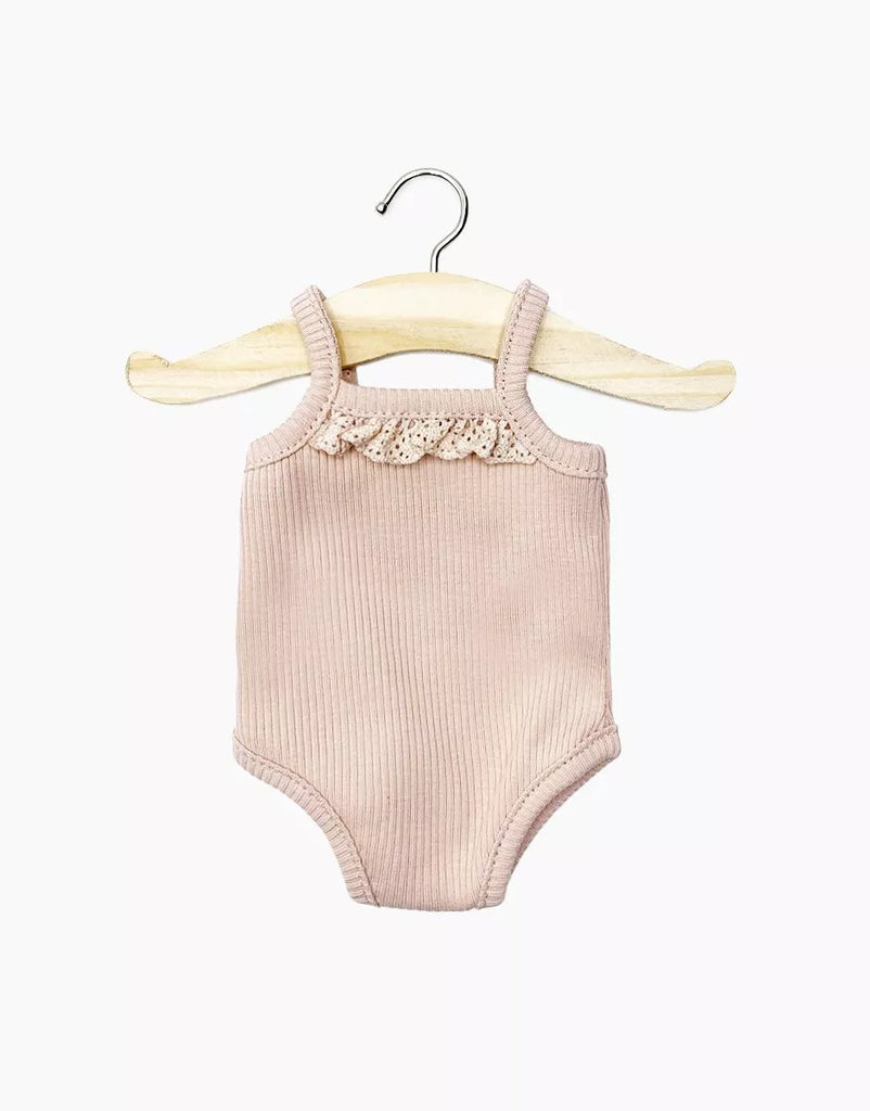 Displayed on a simple wooden hanger against a white background is the Les P'tits Basique Jumpsuit in Petal Ribbed Knit, a pale pink ribbed knit jumpsuit for Minikane Gordis dolls. It features spaghetti straps and a decorative lace trim across the chest.