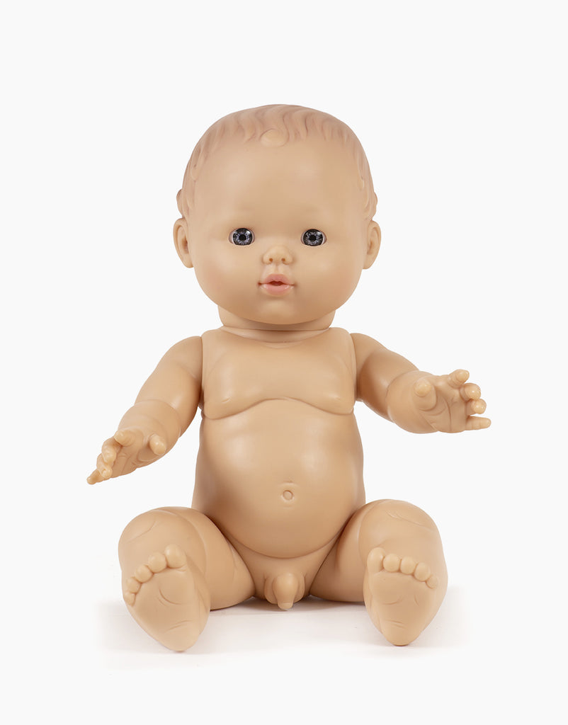 A Minikane Doll (13") - César with Clothing Set, made from phthalate-free vinyl, is positioned against a plain white background. The doll features blue eyes and realistic details, seated with its arms slightly outstretched—ideal for inspiring imaginative playtime.