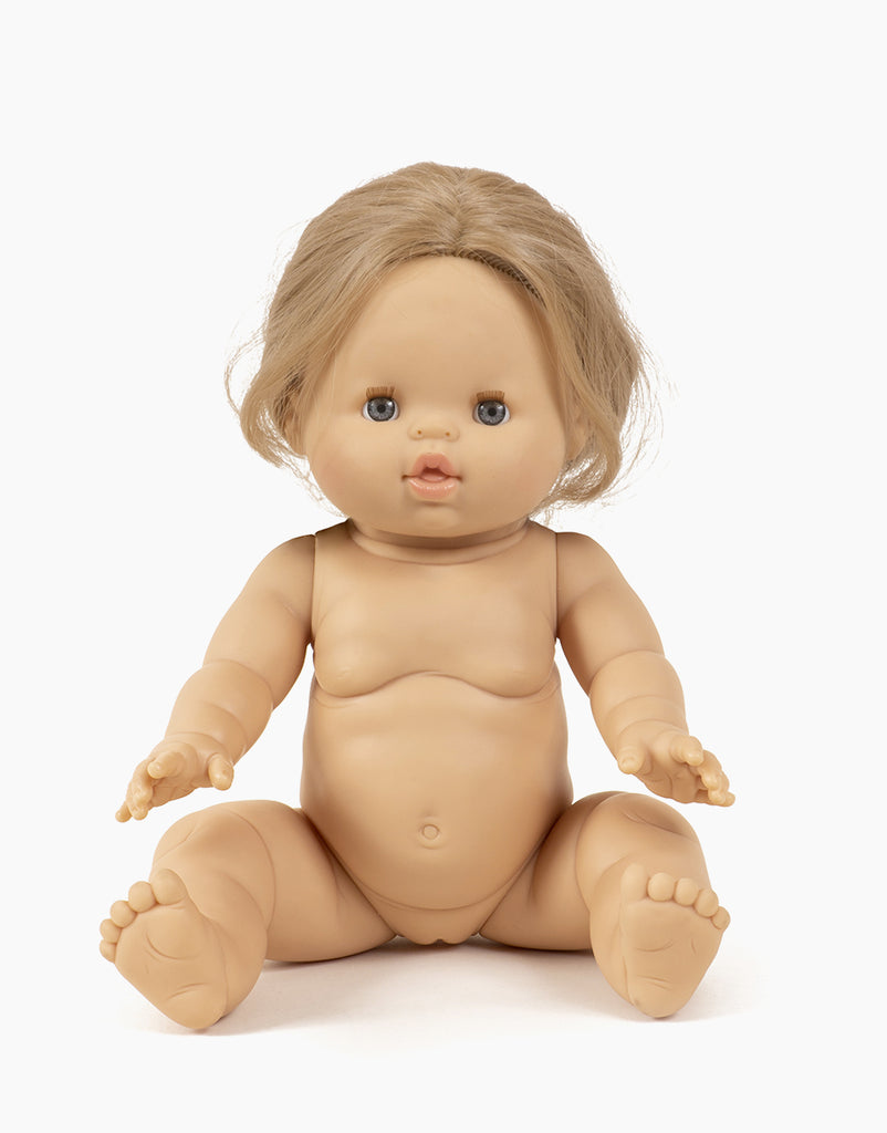 The Minikane Baby Doll (13") - Eleanor, featuring a nude design with a light skin tone, chubby cheeks, and blue eyes, sits upright. It has light brown hair with its arms and legs slightly spread apart. This anatomically correct doll is accented by a hint of vanilla scent against a white background.