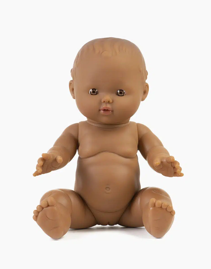 The Minikane Doll (13") - Leonie features brown skin and short hair, is made from phthalate-free vinyl, sits upright with arms and legs slightly outstretched, and is displayed on a plain white background. Clothing sold separately.