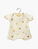 A cream-colored Minikane Doll Clothing Les P'tits Basique Ribbed Bodysuit in Hearts hangs on a wooden hanger, crafted from soft cotton with a golden heart pattern. Designed in France, it adds elegance to any baby's wardrobe and pairs perfectly with Minikane Gordis dolls.