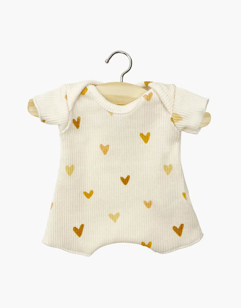 A cream-colored Minikane Doll Clothing Les P'tits Basique Ribbed Bodysuit in Hearts hangs on a wooden hanger, crafted from soft cotton with a golden heart pattern. Designed in France, it adds elegance to any baby's wardrobe and pairs perfectly with Minikane Gordis dolls.