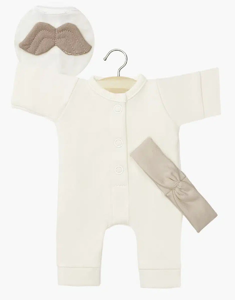 A "Little Angel" Linen Jersey baby onesie in a cream color from Minikane is stylishly presented on a hanger, featuring front buttons. Accompanying the ensemble is a beige headband and a circular pouch embellished with an embroidered mustache design. The minimalist white background enhances the charm of this delightful French-inspired set.