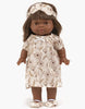 A 14" brown-skinned doll with straight brown hair wears Minikane Doll Clothing: Janelle Sleep Mask in ruffled cotton, plus a matching floral nightgown and slippers, standing against a white background.