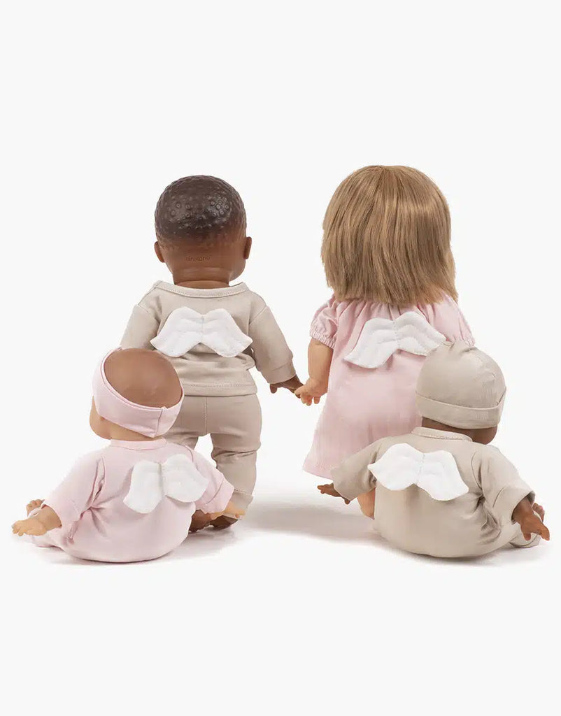 Four 11" Minikane baby dolls, two sitting and two standing, each donning outfits from the “Little Angel” Linen Jersey collection, featuring white angel wings. These dolls showcase varied skin tones and hair colors, exuding charming diversity against a plain white background that echoes the essence of timeless French elegance.