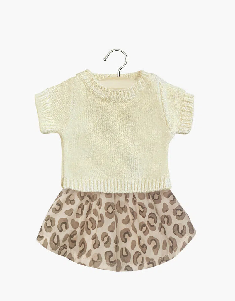 The Minikane Doll Clothing set, featuring the Paula cream sweater and Réjane leopard print light brown tulle skirt, offers a stylish ensemble for dolls. Hand washable, the outfit is elegantly displayed on a wooden hanger against a crisp white background.