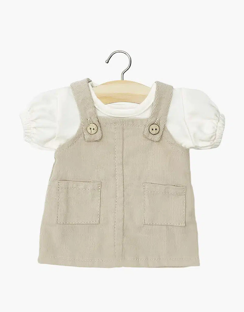 The Minikane Doll Clothing | Nelly Corduroy Dress & T-Shirt set features a beige corduroy dress with button straps and front pockets, layered over an ecru t-shirt—perfectly sized for Minikane Gordis dolls.