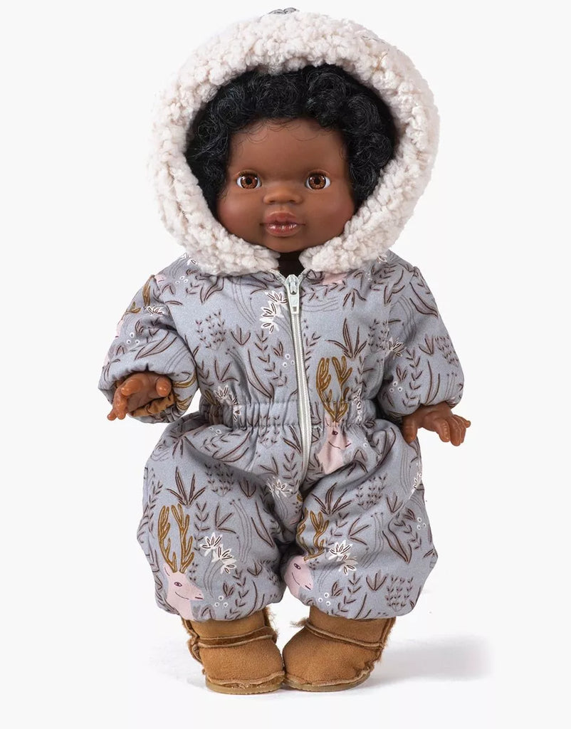 A Minikane doll dressed in the Gigi Elaphe Ski Suit features curly black hair and cozy apparel with charming animal and tree designs. The gray suit is highlighted with earthy tones, paired perfectly with tan boots. Made in France, it includes a hood lined with soft white fluffy fabric for extra warmth.