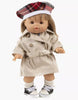 A 13-inch Minikane doll with straight blonde hair models the Tara Trench Coat in Beige Gabardine from Minikane Doll Clothing’s Back to School collection, paired with a plaid beret, white socks, and black-and-white sneakers. Made in France.