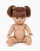 A nude Minikane Baby Doll With Sleeping Eyes (13") - Raphaëlle with brown hair styled in two pigtails and straight bangs sits upright on a white background. The doll has a detailed facial expression, with open eyes and slightly parted lips, and its legs and arms are positioned as if reaching out. It features an anatomically correct design.