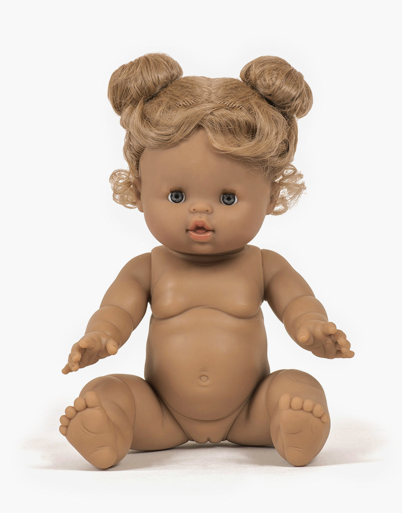 The Minikane Baby Doll (13") - Louise features brown skin, curly blonde hair in two buns, blue eyes, and sits upright. It's anatomically correct, unclothed with legs slightly apart and arms forward. A gentle vanilla scent enhances its charm.