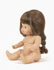 Valentine, a Minikane Baby Doll (13") with light skin and long brown hair styled in a braid, sits upright. This anatomically correct doll has an expressionless face and features a pleasant, natural vanilla scent. The background is plain white. Note that clothing for Valentine is sold separately.