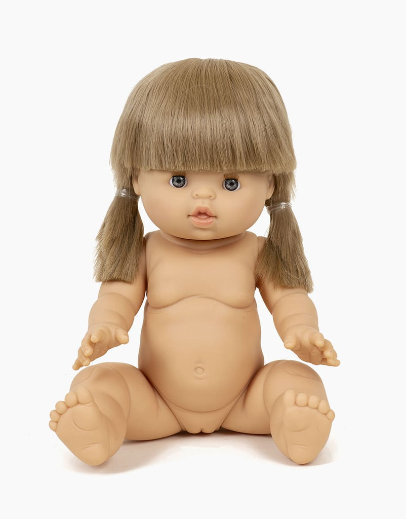A Minikane Baby Doll (13") - Yzé with a beige skin tone, sitting upright. The anatomically correct doll has short, light brown hair styled in two low pigtails, blue eyes, and no clothes. The background is plain white.