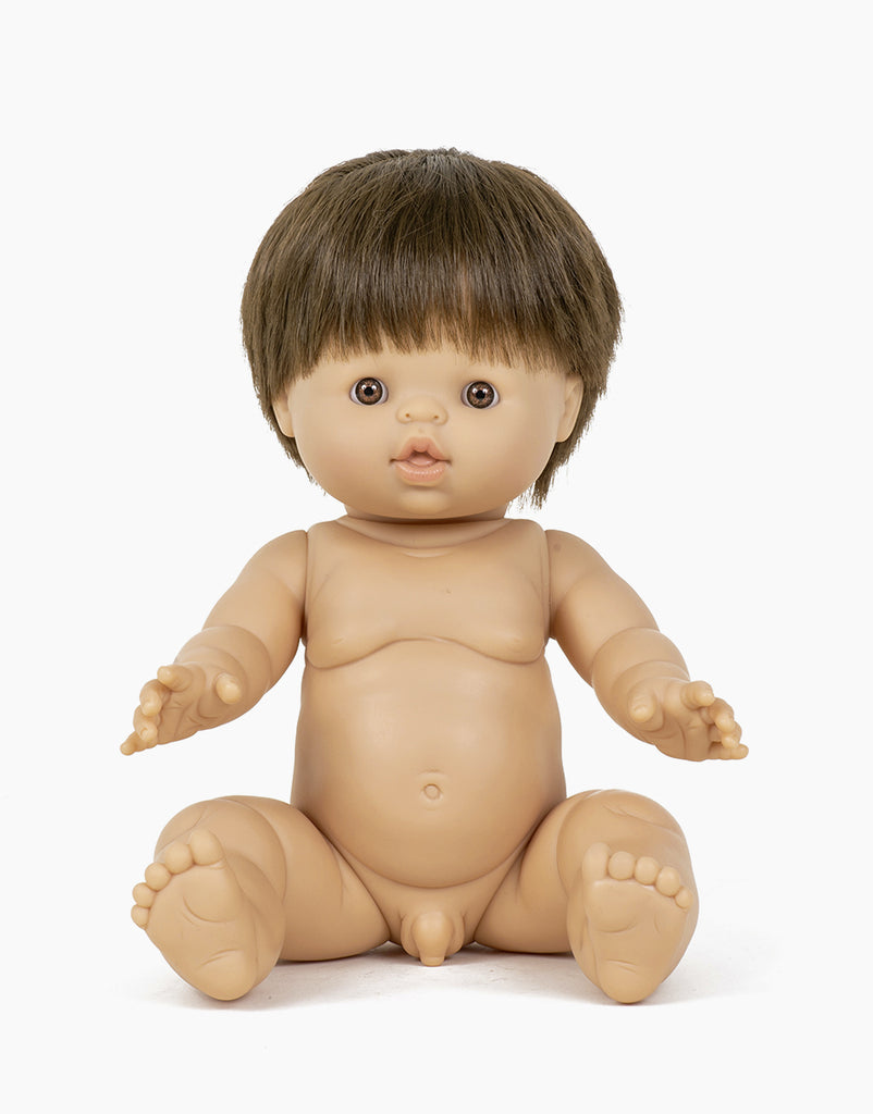 A nude Minikane Baby Doll (13") - Jules with short brown hair is seated with arms extended forward and legs apart. The anatomically correct doll has a realistic body structure, a calm expression, and a hint of natural vanilla scent.