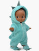 The Minikane Mini Pancha Doll - Arsène with Dinosaur Jumpsuit features a high-quality vinyl doll with brown skin and big eyes, dressed in a fluffy turquoise dinosaur jumpsuit complete with a hood, spikes, and clawed feet—perfect for imaginative play.