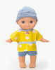 The Minikane Mini Pancha Doll - Basile with Popcorn Painting Outfit is a high-quality vinyl doll featuring a blue hat, blue shorts, and a yellow shirt adorned with popcorn designs, standing upright against a white background—perfect for inspiring imaginative play.