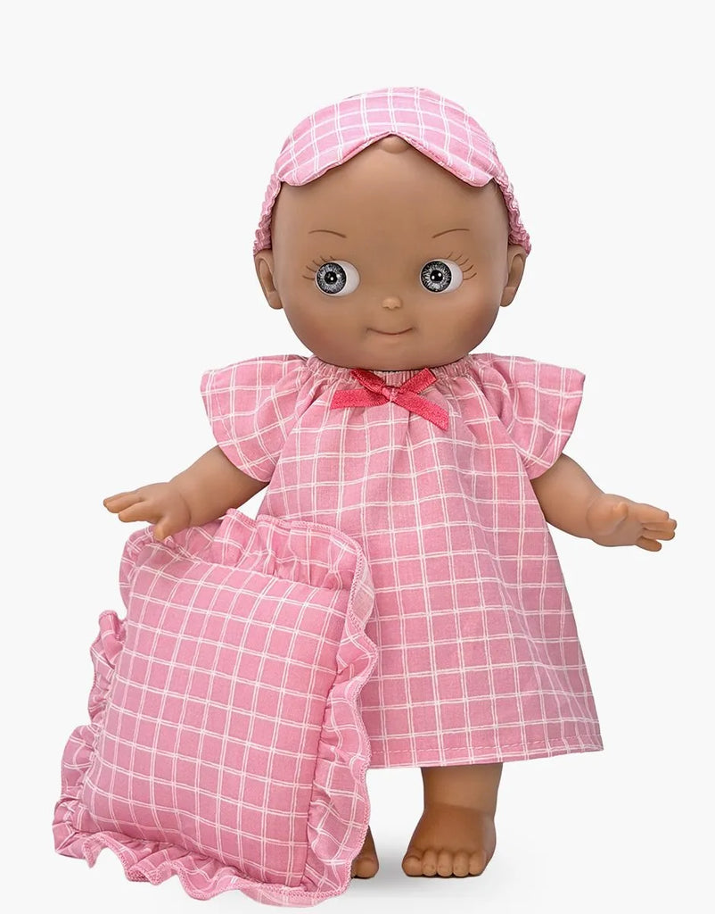 The Mini Pancha Doll - Maia with Pink Checkered Nightgown stands against a white background, wearing a charming pink checkered nightgown and matching sleep mask while holding a ruffled pink checkered pillow—perfect for imaginative play.