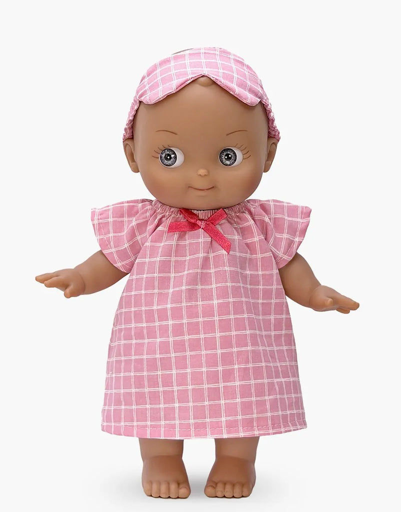 The Mini Pancha Doll - Maia with Pink Checkered Nightgown features big eyes, high-quality vinyl construction, and comes dressed in a pink checkered nightgown with a matching headband. She stands barefoot with arms slightly outstretched against a plain white background—perfect for hours of imaginative play.