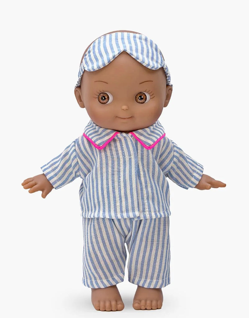 The Minikane Mini Pancha Doll - Noah features blue and white striped pajamas with pink trim and a matching sleep mask, standing barefoot against a plain white background—perfect for imaginative play.