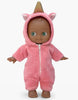 The Mini Pancha Doll - Prunelle with Unicorn Jumpsuit features brown skin and green eyes, dressed in a pink hooded onesie adorned with a unicorn horn and ears. Made from high-quality vinyl, this adorable barefoot doll stands facing forward against a white background, inspiring imaginative play for children.