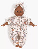 A Minikane 11" doll made in France, dressed in the Lili Jumpsuit & Headband in Jersey - Gisele, featuring a floral-patterned white knit jumpsuit with matching headband, is shown on a white background.