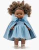A brown-skinned 13-inch Minikane doll with curly brown hair wears the Rosana Short Sleeve Tutu in cobalt blue, with a matching tulle cape and bow, plus cream shoes. She stands against a plain white background.