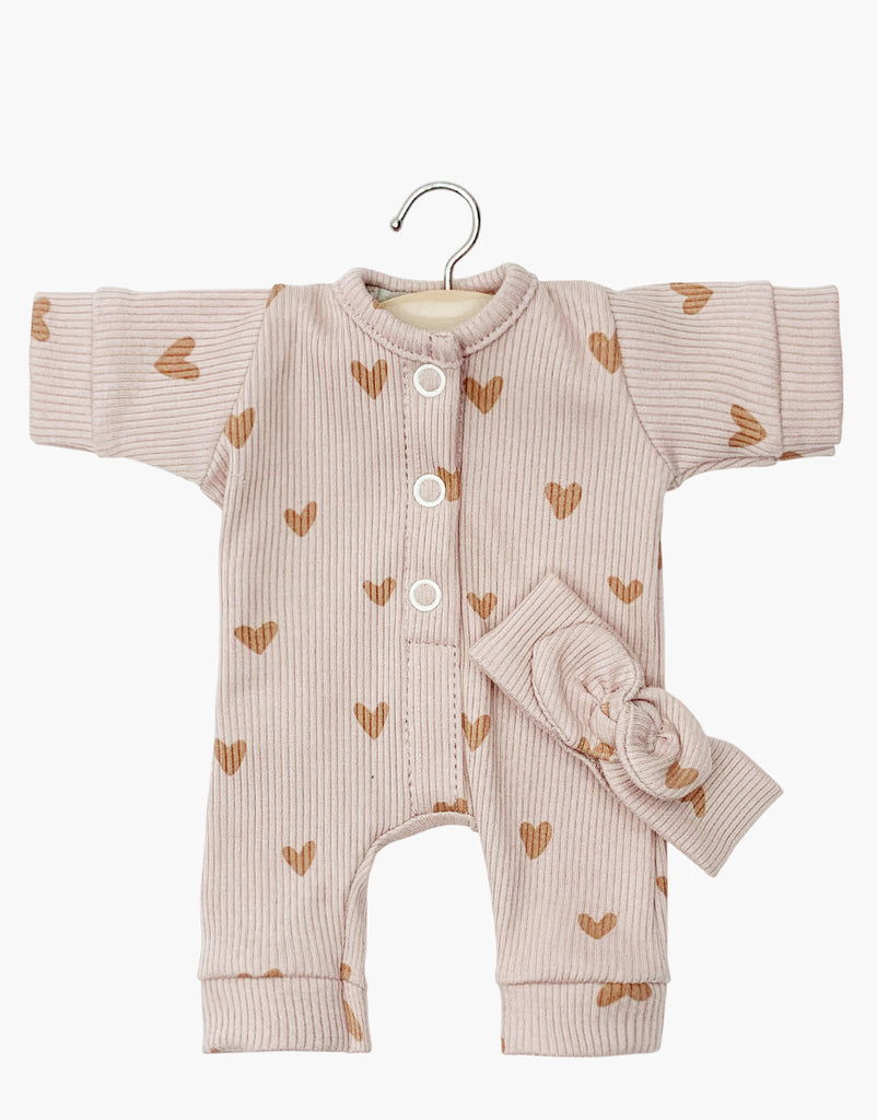 The Minikane Doll Clothing Lili Jumpsuit, made in France, showcases a pink ribbed fabric with brown heart patterns and comes with long sleeves, front buttons, and a matching headband. Ideal for dolls or as a cherished handmade keepsake.