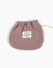 A small, beige, double gauze drawstring fabric bag with a sewn-on label that reads "Minikane Clothing | Romper and Bonnet Set." The bag is crumpled slightly at the top, indicating it is empty or loosely packed—a perfect addition to your collection of Minikane Babies doll accessories.