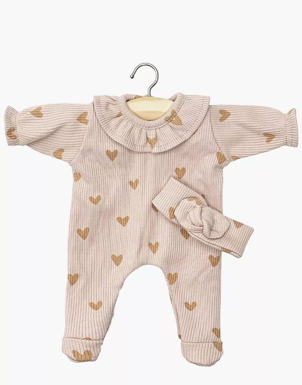 The Minikane 11" Doll Clothing | Camille Onesie & Headband in Ribbed Cotton - Pink Hearts includes a light pink ribbed long-sleeve onesie with a ruffled collar and brown heart patterns, displayed on a hanger with a matching collar and headband beside it.