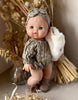 A Minikane doll with blue eyes stands before dried flowers, dressed in the Rylee+Cru Bertille Romper and Headband - Autumn Flowers set, and holds a soft plush bunny.