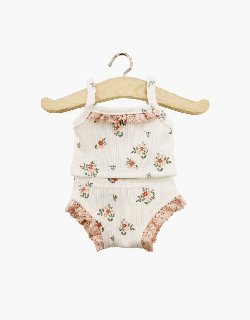 The Minikane Doll Clothing | Les P'tits Basiques - Small Flowers And Lace set hangs on a wooden hanger, featuring a cream ribbed sleeveless top and bottom with pink floral pattern and lace trim on a light background. Hand washable for easy care.