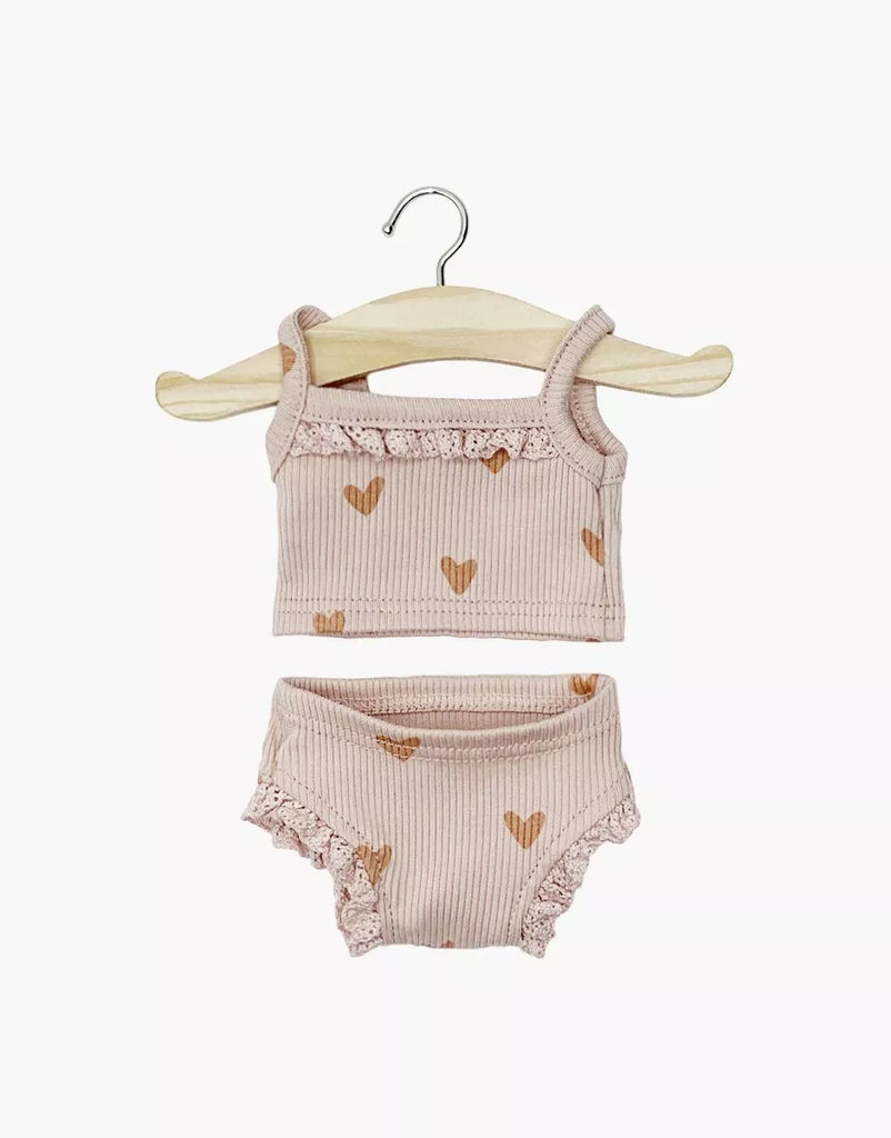 The Minikane Doll Clothing | Les P'tits Basiques 2-piece set in ribbed cotton features a pink hearts tank top and ruffled shorts, displayed on a small wooden hanger—perfect underwear for Minikane dolls.