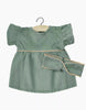 The Minikane Doll Clothing, Daisy Dress with Headband in Sage Green features a corduroy baby dress with puffy short sleeves and a matching headband, designed in France. Hand washable and displayed on a hanger against a white background, it perfectly coordinates style and practicality for Minikane dolls.