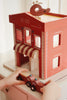 A child plays with a Konges Sloejd - Wooden Fire Station and a fire engine.