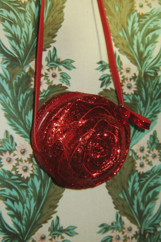 Konges Sloejd Rose Shoulder Bag in red glitter, shaped like a rose with a slim shoulder strap and zipper closure.
