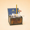 A charming handcrafted birthday decoration, the Mother Goose Cake Topper – Final Sale features a decorative goose figure holding a candle on its back, nestled inside a wooden treasure chest. Accompanied by a small cloth bag and some dried flowers, this unique collectible keepsake is enhanced by a starry blue card with festive text in the background.