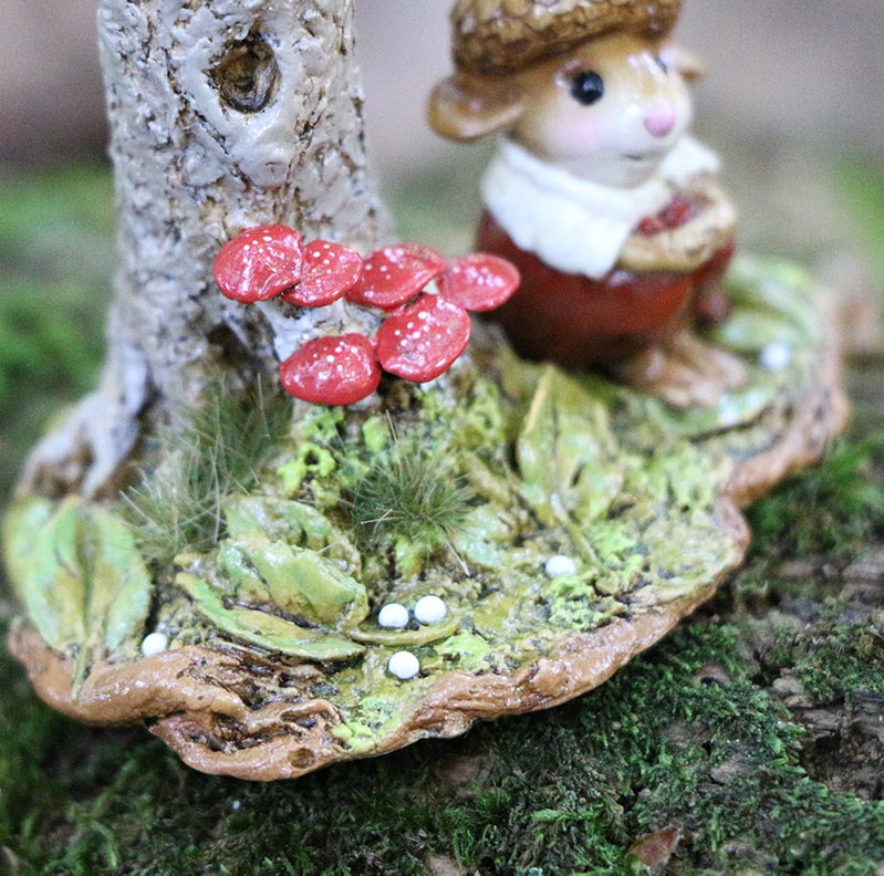 The Wee Forest Folk Tiny Collectible "My Happy Place" features a mouse in a brown hat and red coat beside a tree with red mushrooms, green leaves, and white pebbles—hand-sculpted miniatures handmade in the USA. Not a toy.