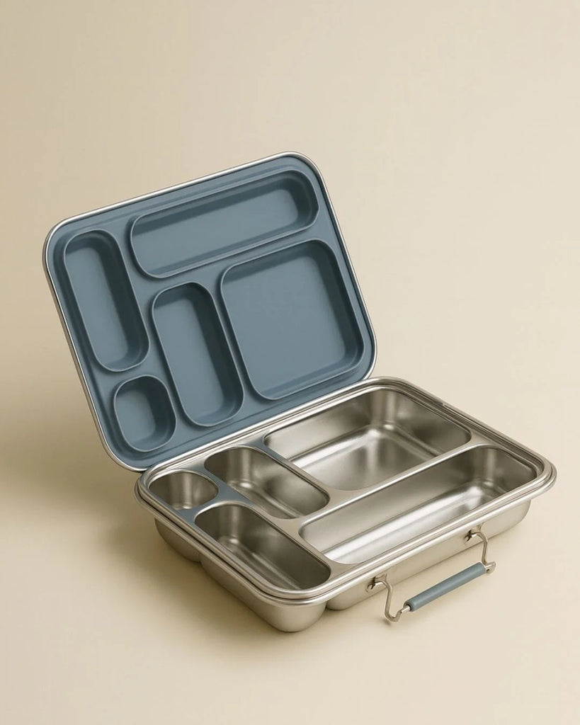An open Haps Nordic - Stainless Steel Lunch Box - Multi-Compartment (Ocean) with a blue, sectioned lid showcases its multiple food storage compartments against a beige background. This bento lunch box is ideal for keeping your meals organized and fresh.
