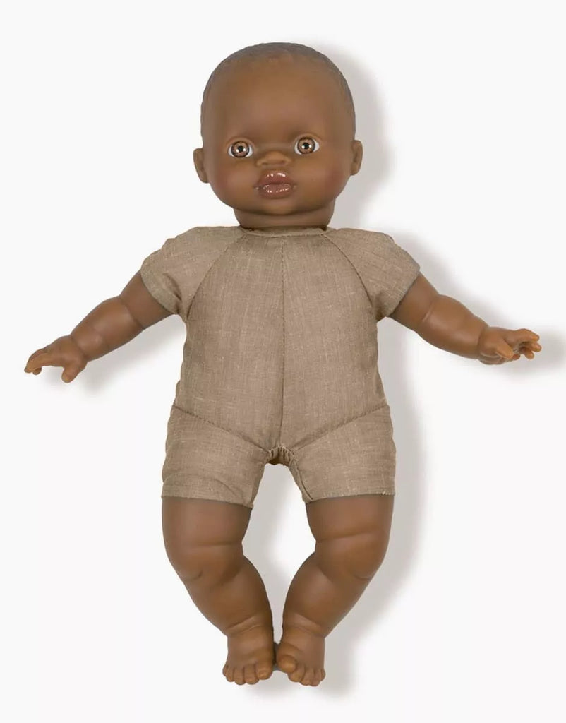 The Minikane Soft Body Doll (11") - Ondine, featuring dark skin and short hair, is dressed in a simple beige onesie. Crafted from phthalate-free vinyl, this doll has a neutral facial expression and is positioned upright against a plain white background, making it an ideal bedtime companion.