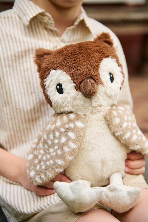 A child, wearing a beige and white striped shirt, clutches Oscar The Owl Stuffed Animal, featuring a plush brown and cream fur with large eyes and a soft texture. The child resembles a bohemian wanderer on an imaginative adventure.