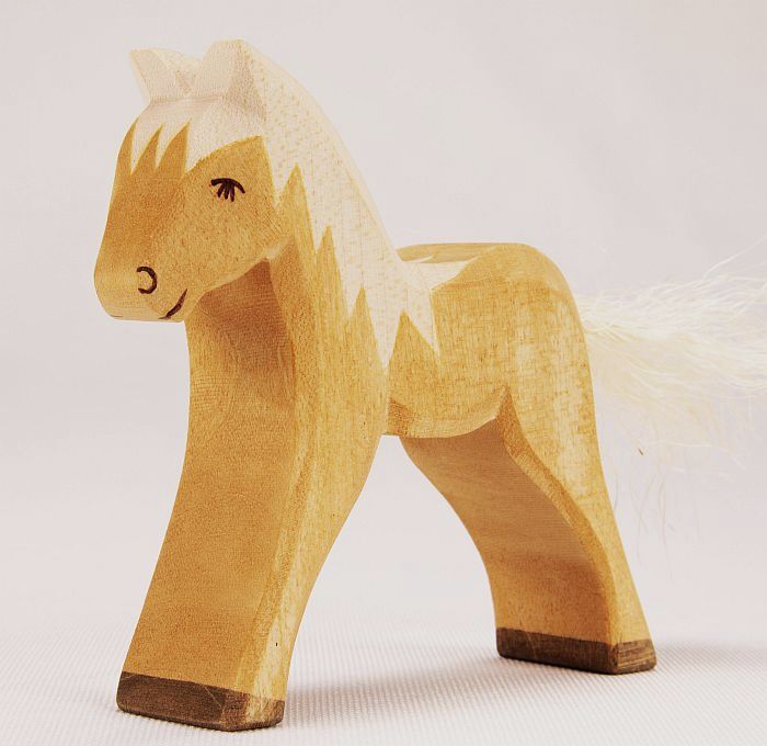 A Ostheimer Horse with a simplistic design, featuring a pale natural wood finish and a fluffy white tail, standing against a neutral backdrop. This handcrafted wooden toy encourages imaginative play.