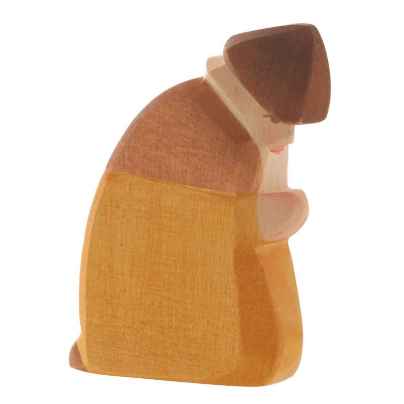 A handcrafted Ostheimer Shepherd - Kneeling figurine, crafted with a mix of light and dark wood, emphasizing simplicity and abstract form.