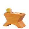 Wooden figurine of Ostheimer Baby Jesus sitting in a star-shaped base, painted with natural tones and a simplistic, handcrafted design. The child, reminiscent of Ostheimer toys, has painted features and blond hair.