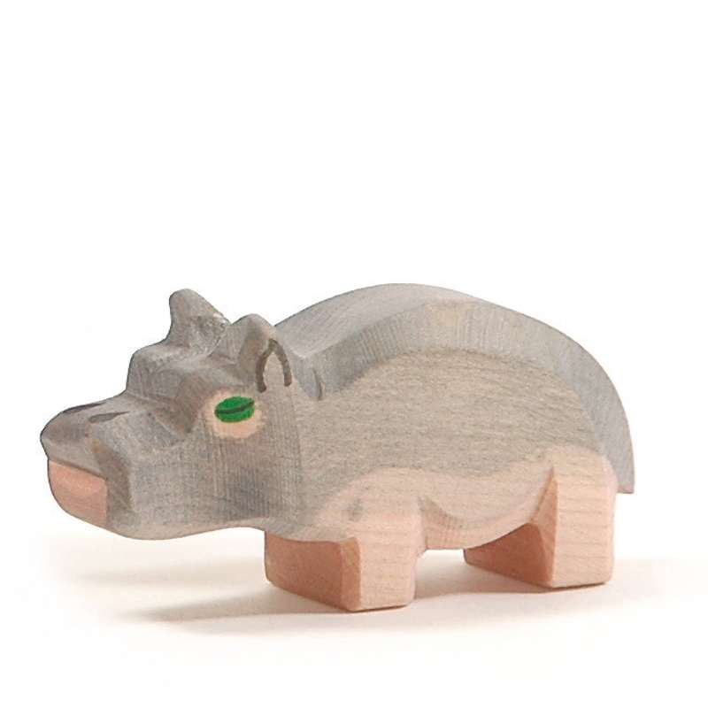 A handcrafted wooden Ostheimer Hippopotamus - Small with a simple design, painted in light beige with green eyes, standing isolated on a white background.