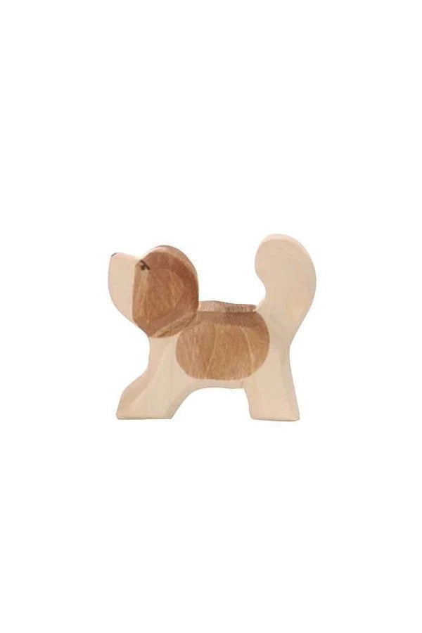 A small, wooden Ostheimer Small Saint Bernhard Dog - Head Up with a light natural finish. Handcrafted from sustainably sourced materials, the dog has rounded shapes with darker brown patches on its body, ears, and tail, giving it a charming and simplistic design. Its tail is curled upwards as it stands on four short legs.